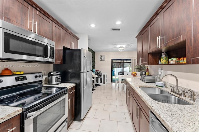 kitchen featuring sink, stainless steel appliances, light tile patterned flooring, and light stone countertops