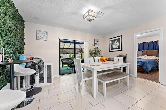 dining area featuring a textured ceiling and light tile patterned floors