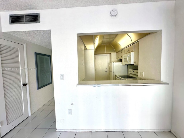 kitchen with white appliances, kitchen peninsula, a textured ceiling, and light tile patterned flooring