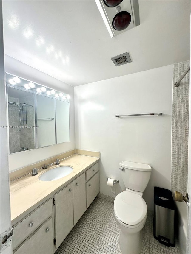 bathroom featuring toilet, a shower, tile patterned floors, and vanity