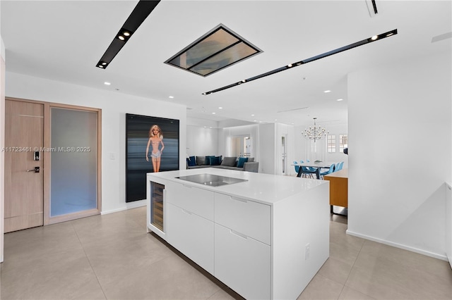 kitchen featuring white cabinetry, black electric cooktop, a chandelier, a kitchen island with sink, and wine cooler