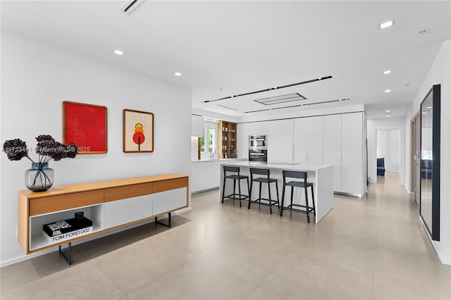 interior space with a kitchen island, white cabinetry, and a kitchen bar