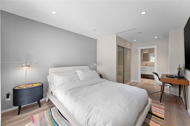 bedroom with ensuite bath, a closet, and light hardwood / wood-style floors