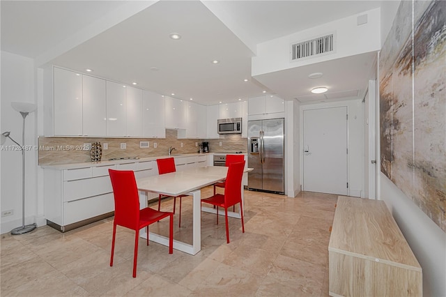 kitchen featuring decorative backsplash, white cabinetry, and appliances with stainless steel finishes