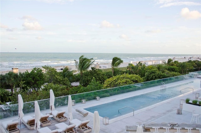 view of swimming pool with a beach view and a water view