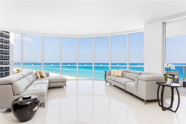 living room featuring light tile patterned flooring, a beach view, and a water view