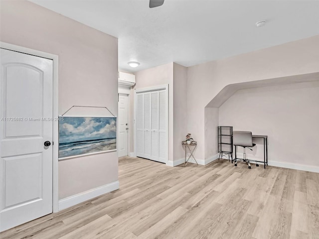 additional living space featuring a wall unit AC and light hardwood / wood-style floors