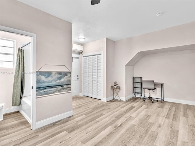 additional living space featuring a wall unit AC and light hardwood / wood-style flooring