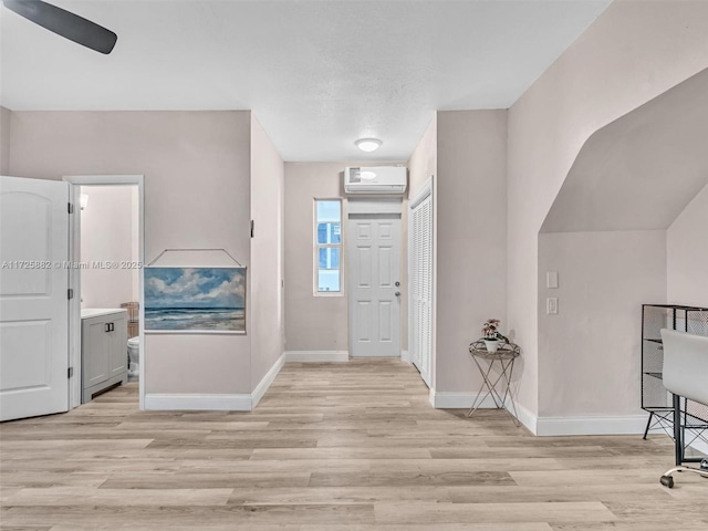 entrance foyer featuring ceiling fan, a wall mounted AC, and light hardwood / wood-style floors