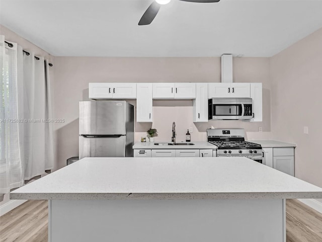 kitchen with sink, ceiling fan, white cabinetry, stainless steel appliances, and light wood-type flooring