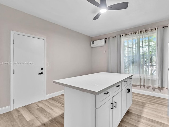 kitchen featuring white cabinetry, a center island, ceiling fan, a wall unit AC, and light hardwood / wood-style flooring