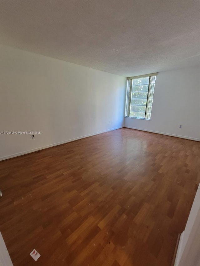 spare room with a textured ceiling and hardwood / wood-style floors