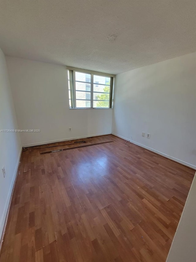 spare room featuring a textured ceiling and hardwood / wood-style flooring