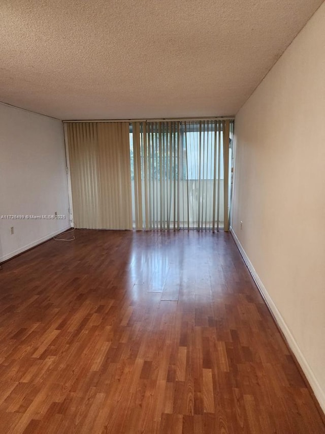 unfurnished room featuring dark wood-type flooring, a textured ceiling, and a wall of windows