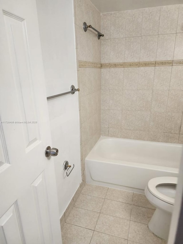 bathroom featuring toilet, tiled shower / bath combo, and tile patterned flooring