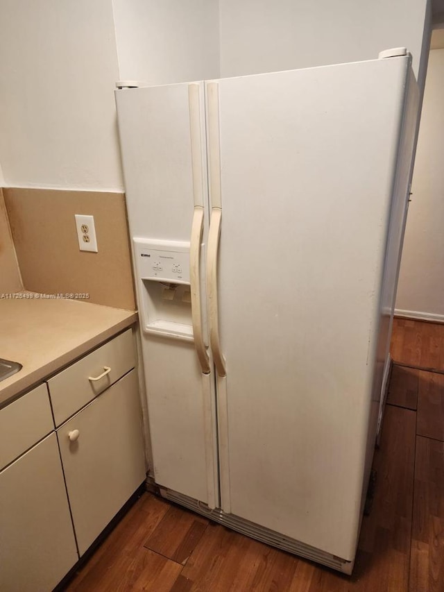 kitchen featuring white cabinets, dark wood-type flooring, and white fridge with ice dispenser