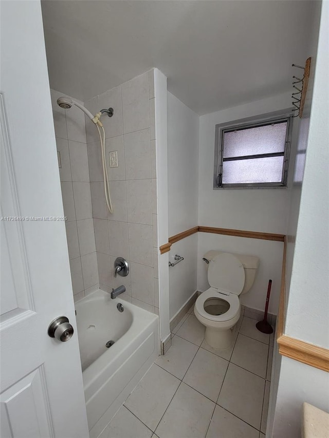 bathroom featuring toilet, tiled shower / bath combo, and tile patterned floors