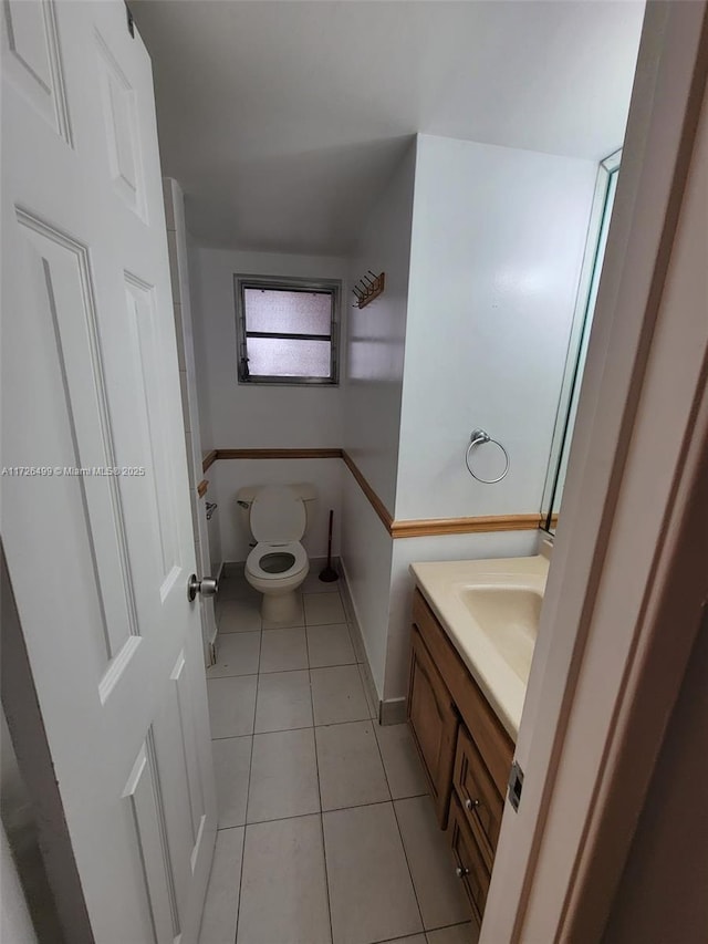 bathroom with toilet, sink, and tile patterned floors