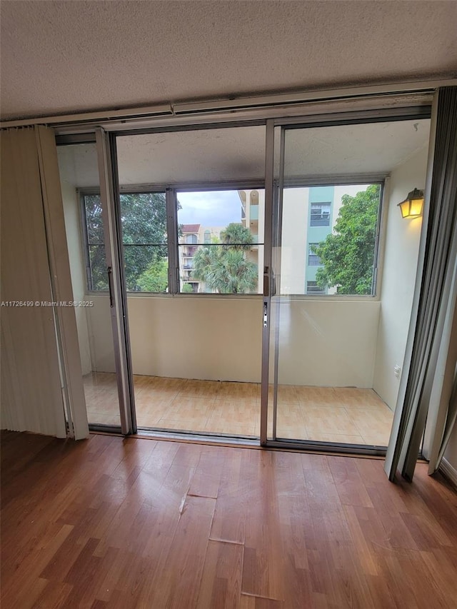 doorway to outside with a textured ceiling, hardwood / wood-style floors, and plenty of natural light