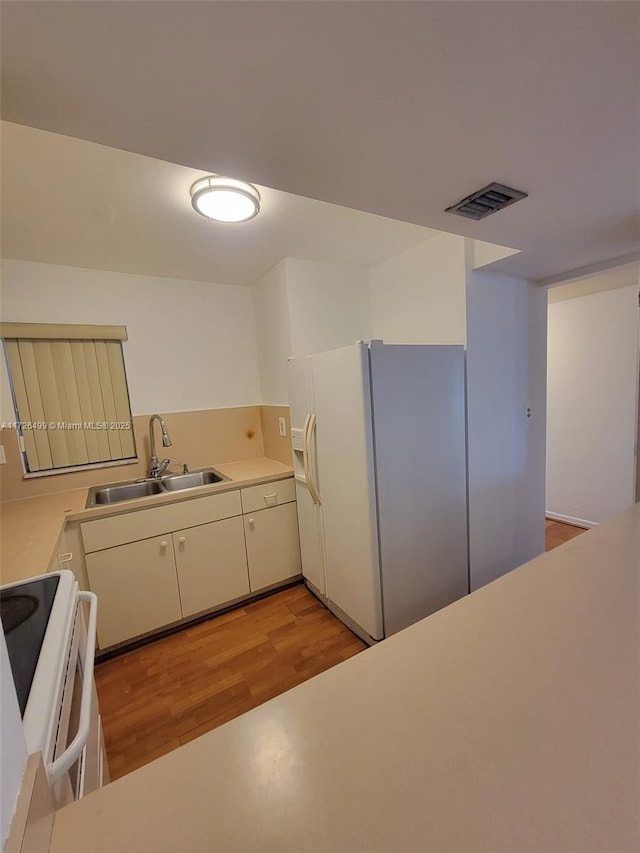 kitchen with electric range, sink, white fridge with ice dispenser, and light hardwood / wood-style floors