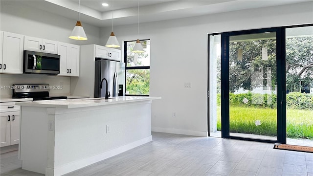 kitchen featuring hanging light fixtures, stainless steel appliances, a center island with sink, white cabinetry, and sink