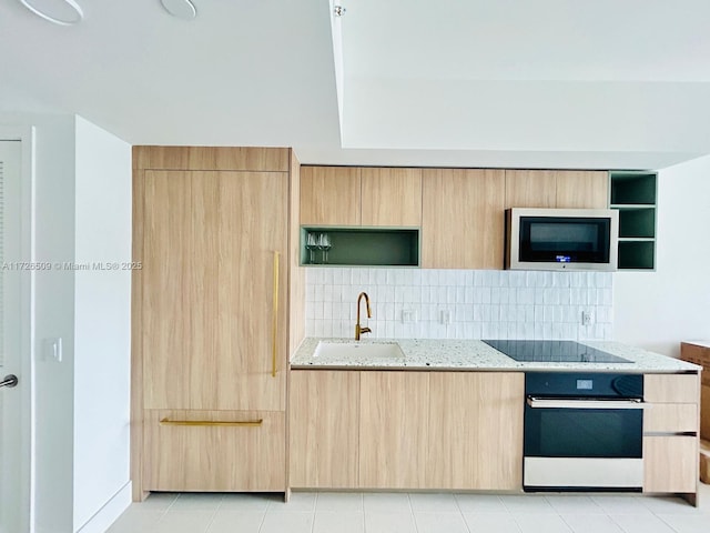 kitchen featuring light stone counters, wall oven, tasteful backsplash, black electric stovetop, and sink