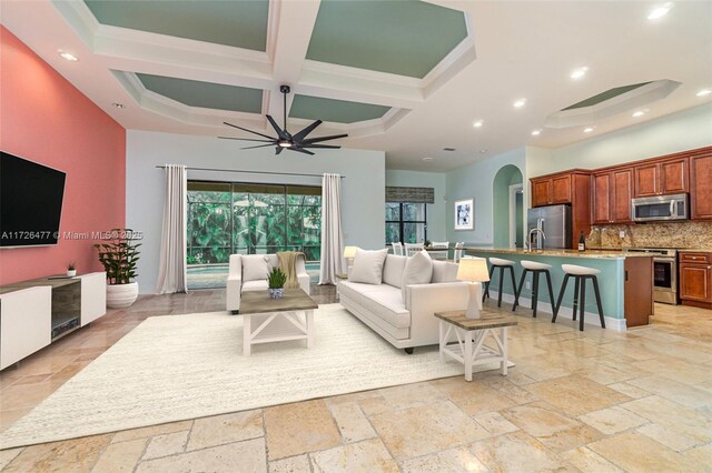 living room with sink, coffered ceiling, ceiling fan, crown molding, and beam ceiling