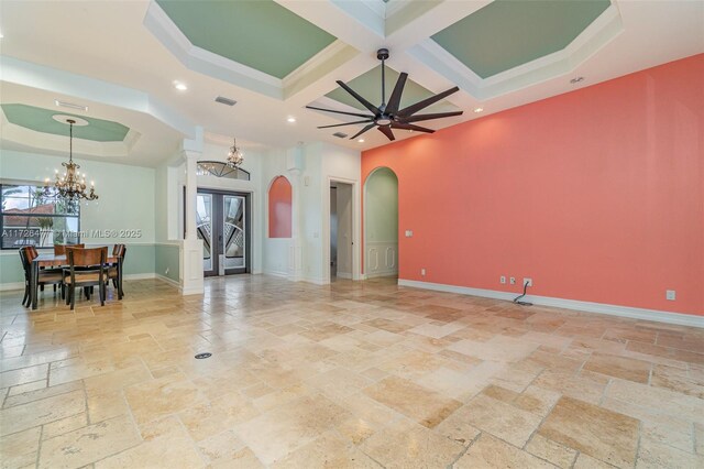 living room with a healthy amount of sunlight, coffered ceiling, ceiling fan with notable chandelier, and a tray ceiling