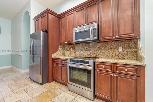 kitchen featuring light stone counters, stainless steel appliances, and decorative backsplash