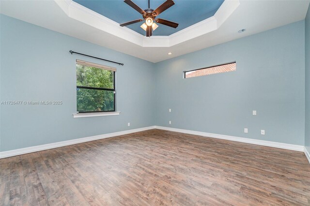 unfurnished room featuring ceiling fan, ornamental molding, wood-type flooring, and a raised ceiling