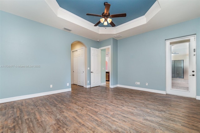 unfurnished room with a raised ceiling, ornamental molding, dark hardwood / wood-style floors, and ceiling fan