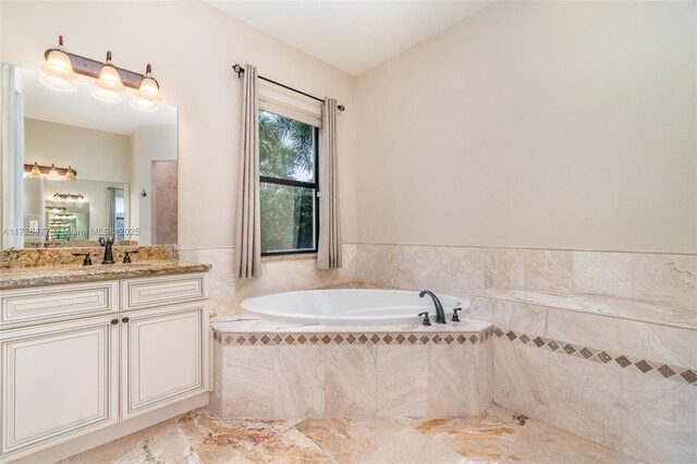 bathroom with tiled tub and vanity