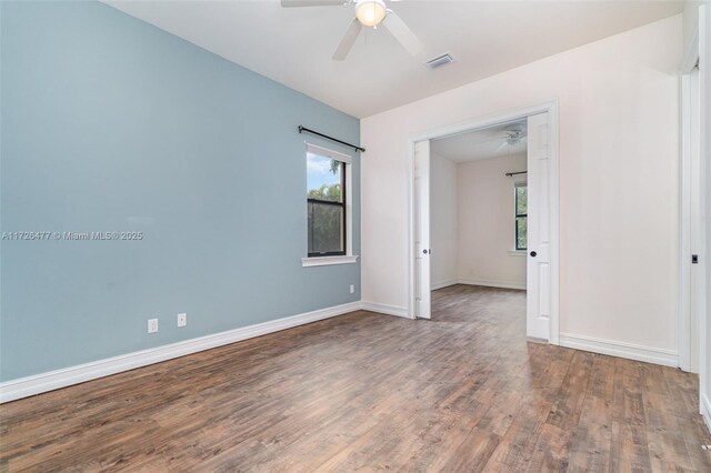 empty room with dark wood-type flooring and ceiling fan