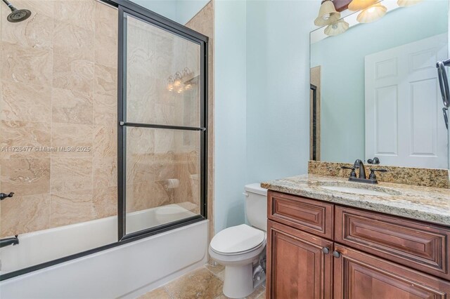 full bathroom featuring vanity, shower / bath combination with glass door, and toilet