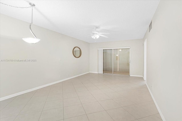 tiled spare room with a textured ceiling and ceiling fan