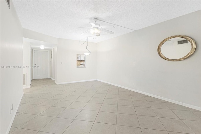 empty room with ceiling fan, light tile patterned flooring, and a textured ceiling