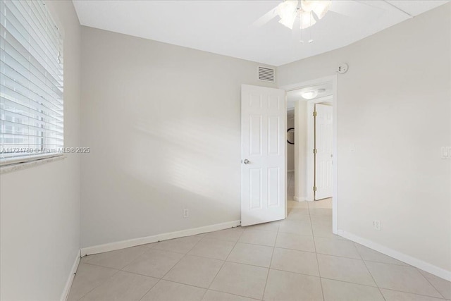 spare room with ceiling fan and light tile patterned floors