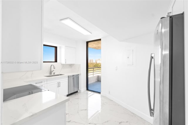 kitchen with light stone countertops, decorative backsplash, white cabinetry, appliances with stainless steel finishes, and sink