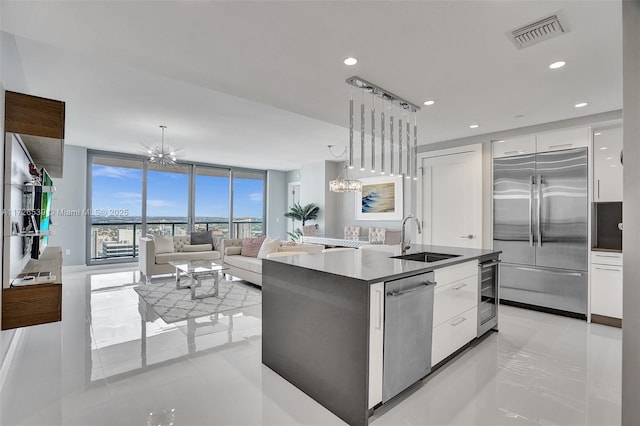 kitchen featuring appliances with stainless steel finishes, a wall of windows, hanging light fixtures, sink, and white cabinetry