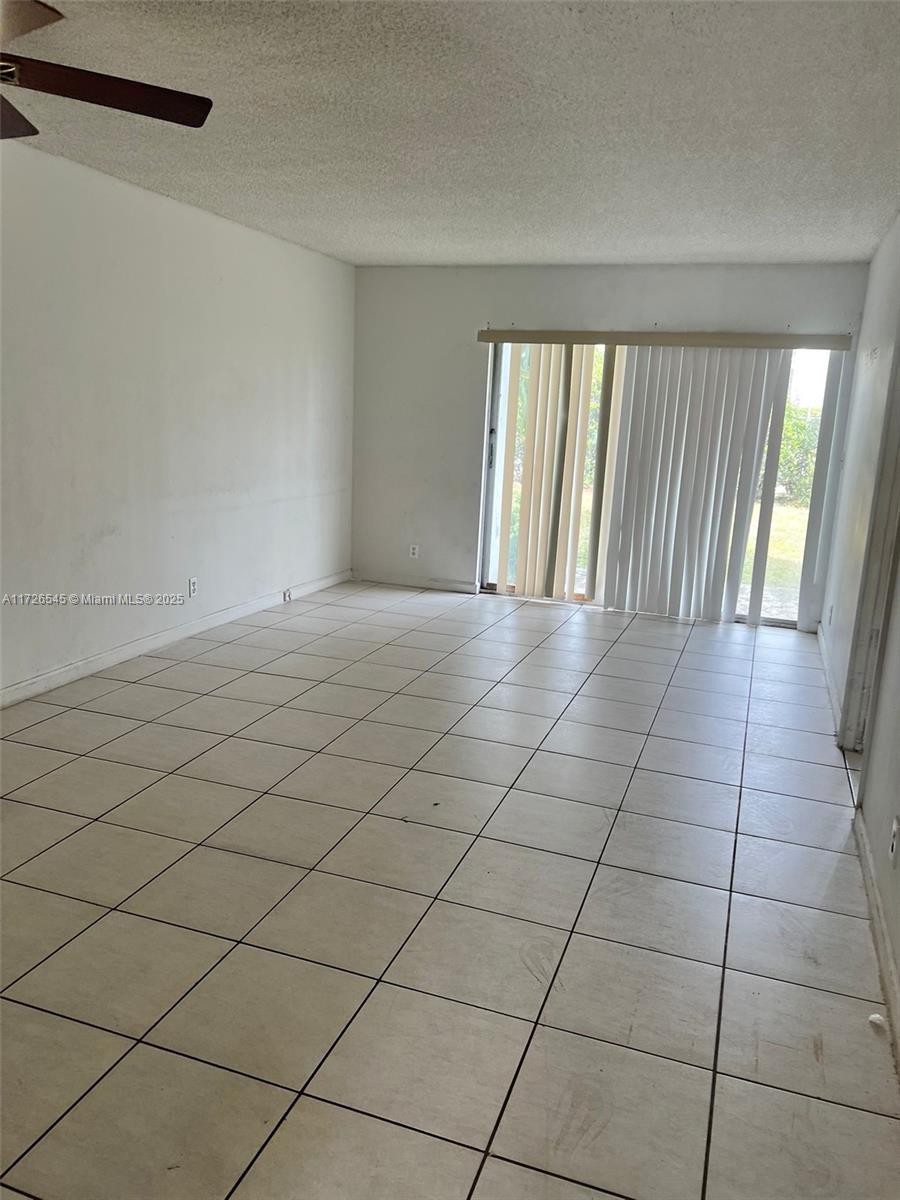 unfurnished room featuring a textured ceiling, ceiling fan, and light tile patterned floors