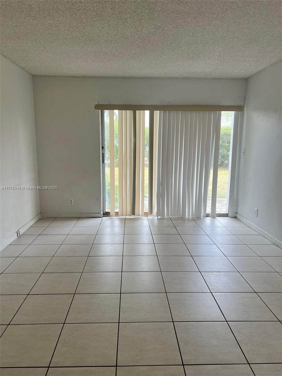 tiled spare room featuring a textured ceiling