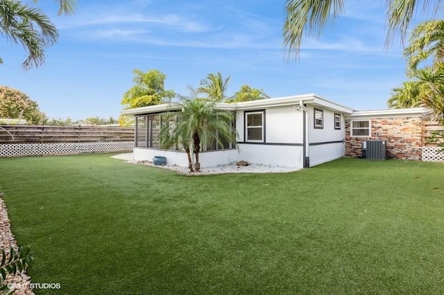 back of property featuring central AC unit, a yard, and a sunroom