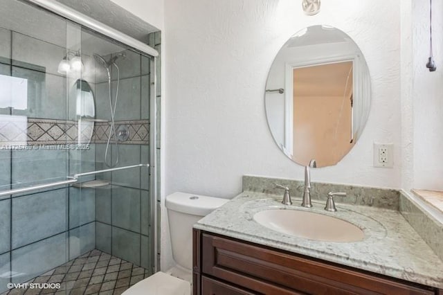 bathroom featuring vanity, a shower with door, and toilet