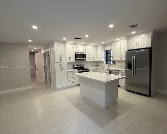 kitchen featuring sink, stainless steel appliances, white cabinetry, and a center island