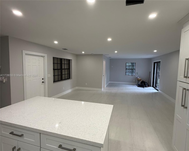 kitchen featuring a center island, light stone countertops, and white cabinetry