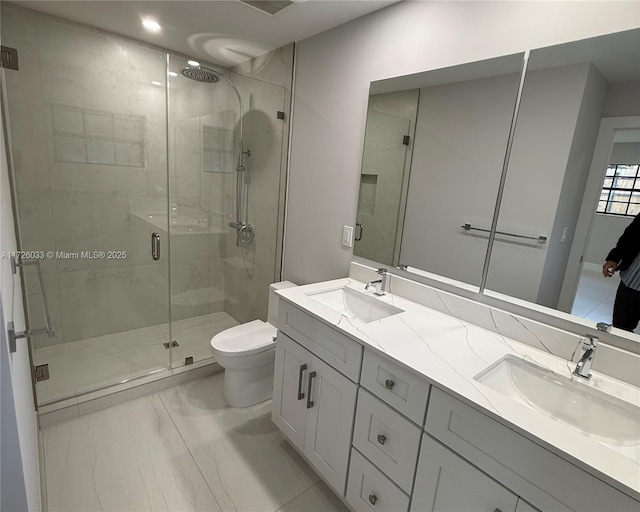 bathroom with toilet, vanity, and a shower with shower door