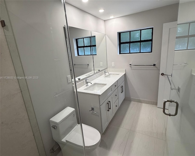 bathroom featuring a healthy amount of sunlight, a shower with shower door, vanity, and toilet