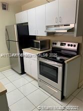 kitchen featuring light tile patterned flooring, white cabinetry, and appliances with stainless steel finishes