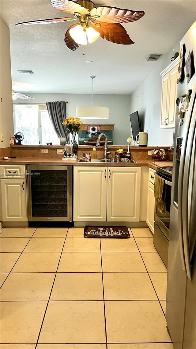 kitchen featuring wine cooler, sink, light tile patterned floors, kitchen peninsula, and stainless steel appliances