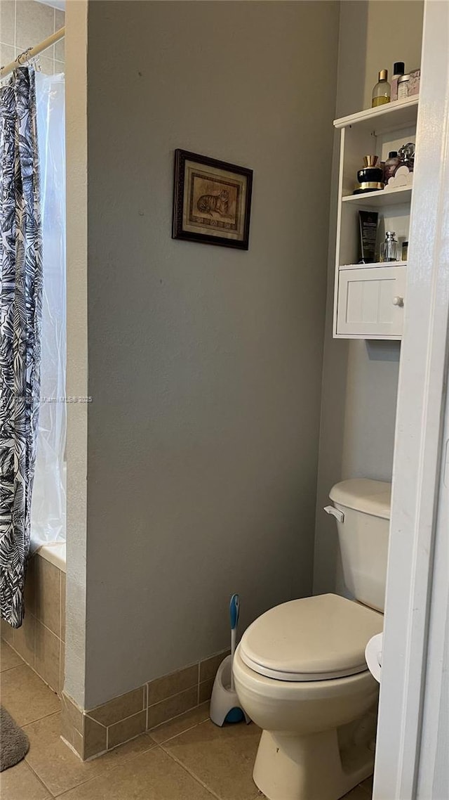 bathroom featuring tile patterned flooring, shower / bath combo with shower curtain, and toilet